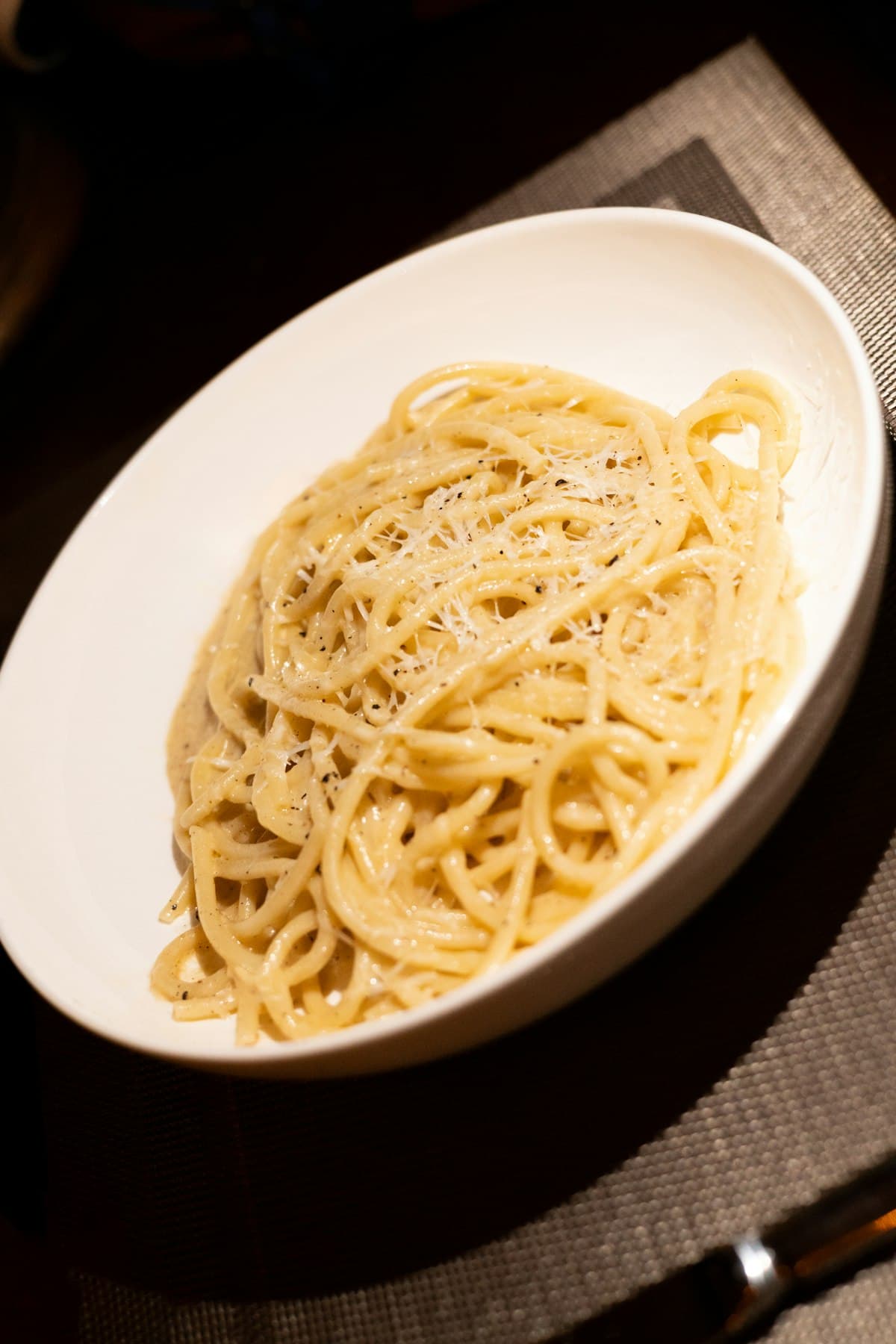 Een bord spaghetti cacio e pepe met een romige pecorinosaus en flink wat versgemalen zwarte peper.