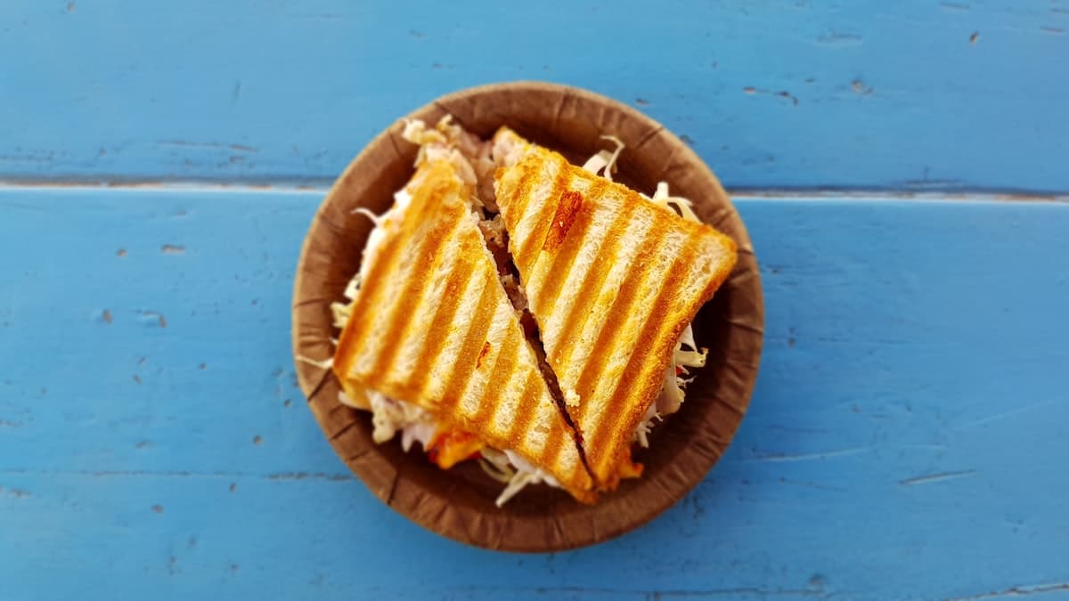 Een krokant gegrilde kaassandwich, doormidden gesneden, met kimchi en gesmolten kaas die tussen het brood vandaan piept.